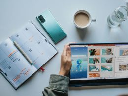 person using Windows 11 computer beside white ceramic mug on white table