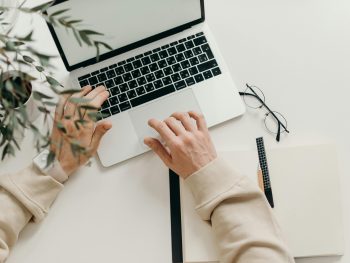 Free An overhead view of a person working on a laptop in a minimalist home office setting. Stock Photo