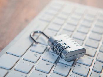 A combination lock rests on a computer keyboard.