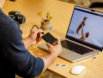 A man sitting at a table with a laptop and cell phone