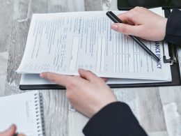 Free Close-up of hands analyzing insurance policy paperwork with pen on table. Stock Photo