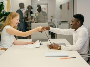 Free Business professionals completing a successful deal with a handshake in a modern office setting. Stock Photo
