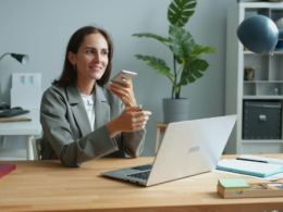 lady holding phone while working on a laptop